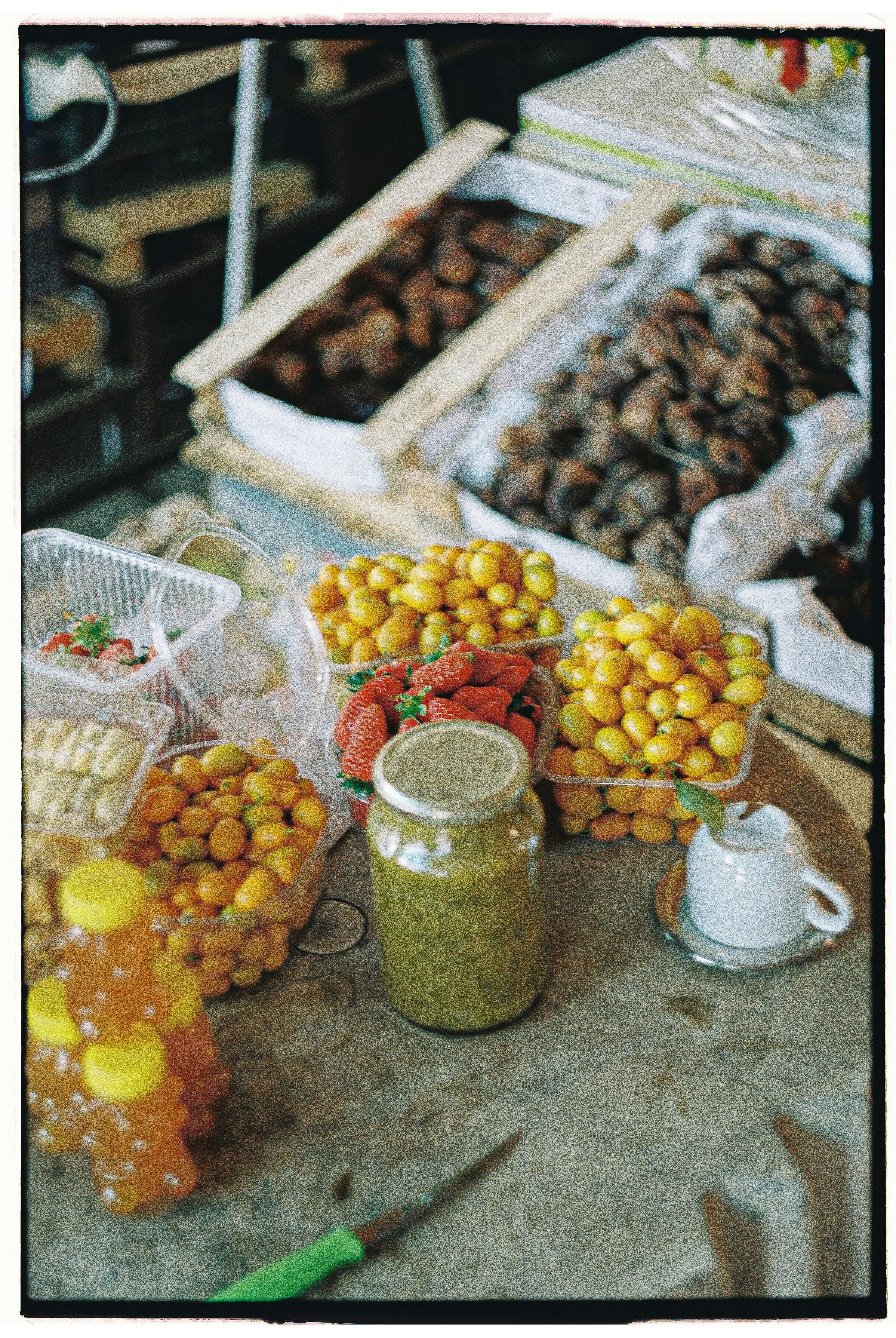 A colorful display of fruits and preserves at a bustling market stall.