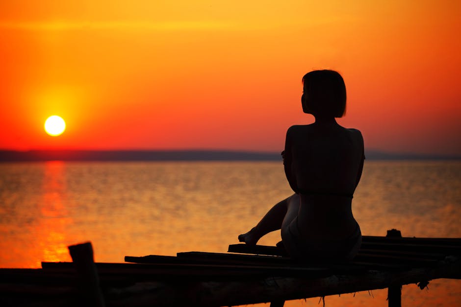 Silhouette of Woman Sitting on Dock during Sunset · Free Stock Photo
