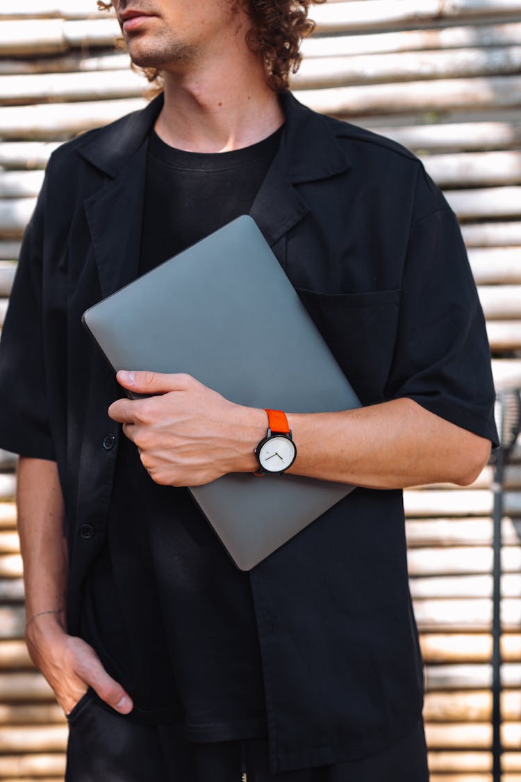 Standing Man Holding A Laptop Under Arm