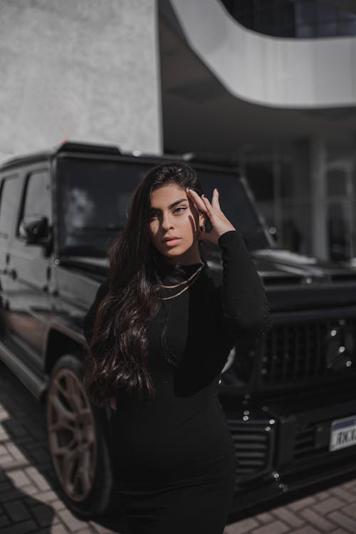 Young Brunette Standing in front of a Black Car 