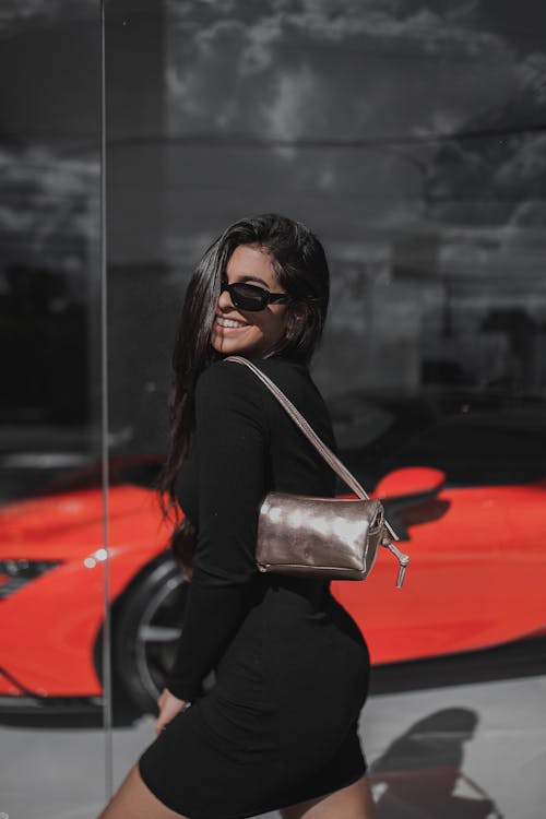 Young Brunette in a Black Dress Posing in front of a Car Salon 