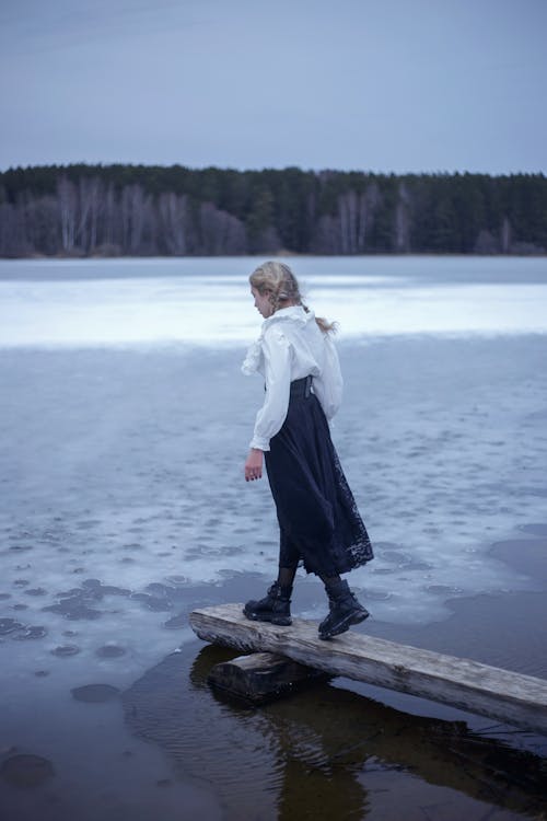 Woman Standing on a Wooden Board on the Shore of a Frozen Lake 