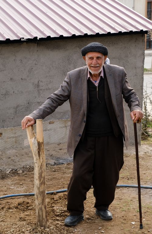 Free Elderly man in flat cap leaning on cane, smiling outdoors in casual attire. Stock Photo