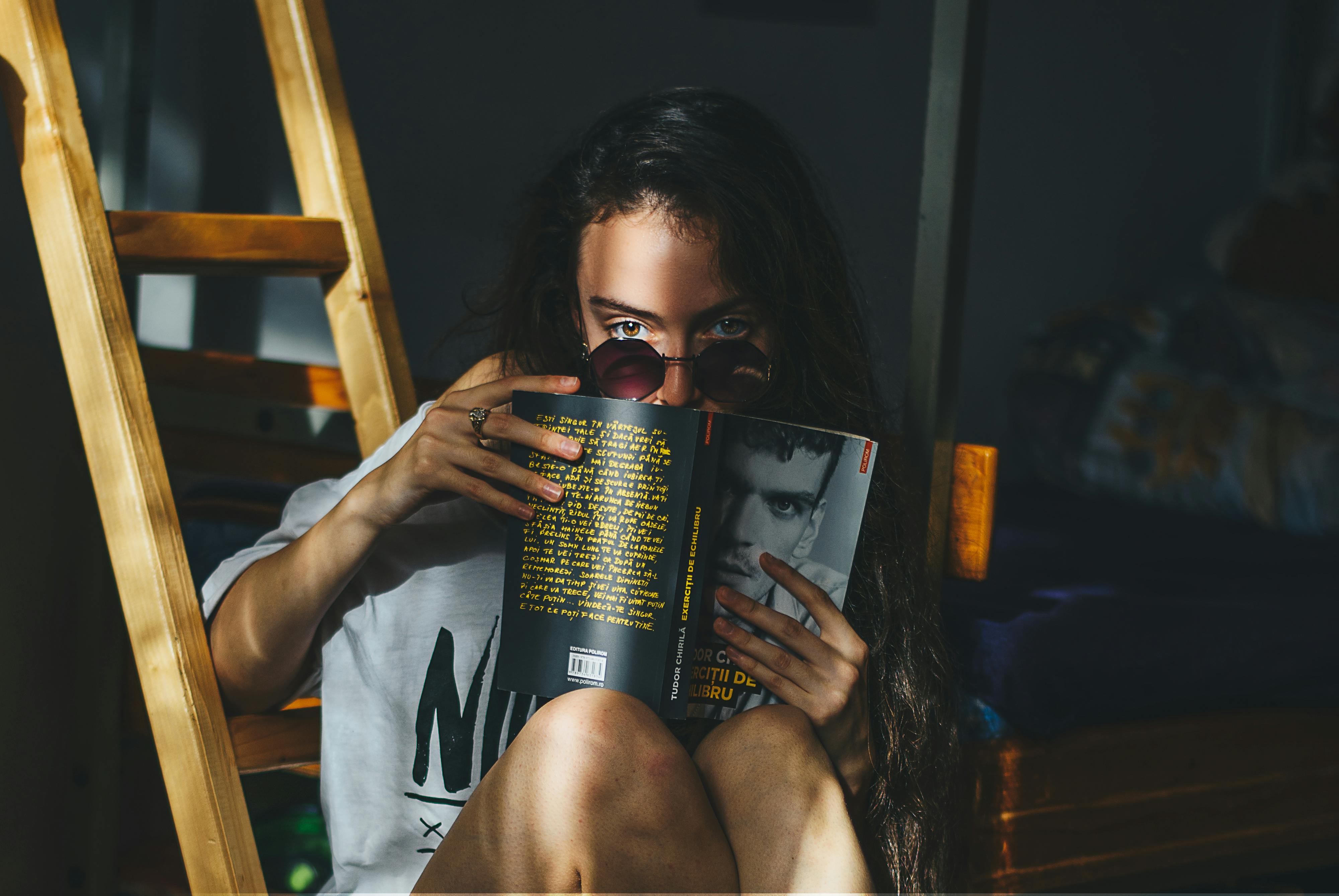 woman reading magazine beside brown wooden ladder