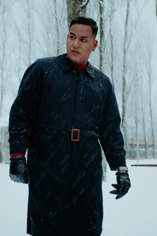 Free Stylish man in a black coat poses in a snowy park, emphasizing winter fashion. Stock Photo