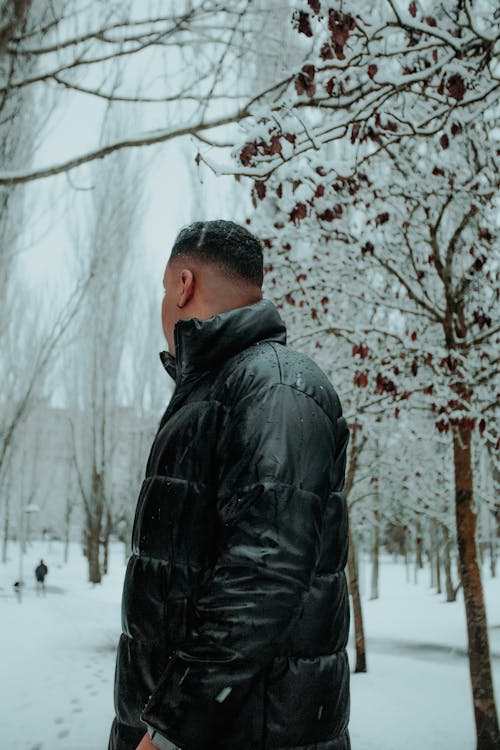 Man in a Jacket Standing in a Snowy Park 