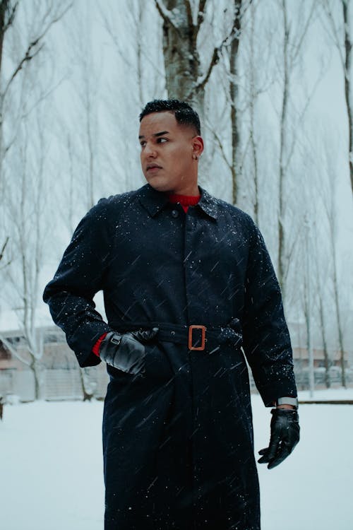 Man in a Black Coat Standing in a Park during a Snowfall 