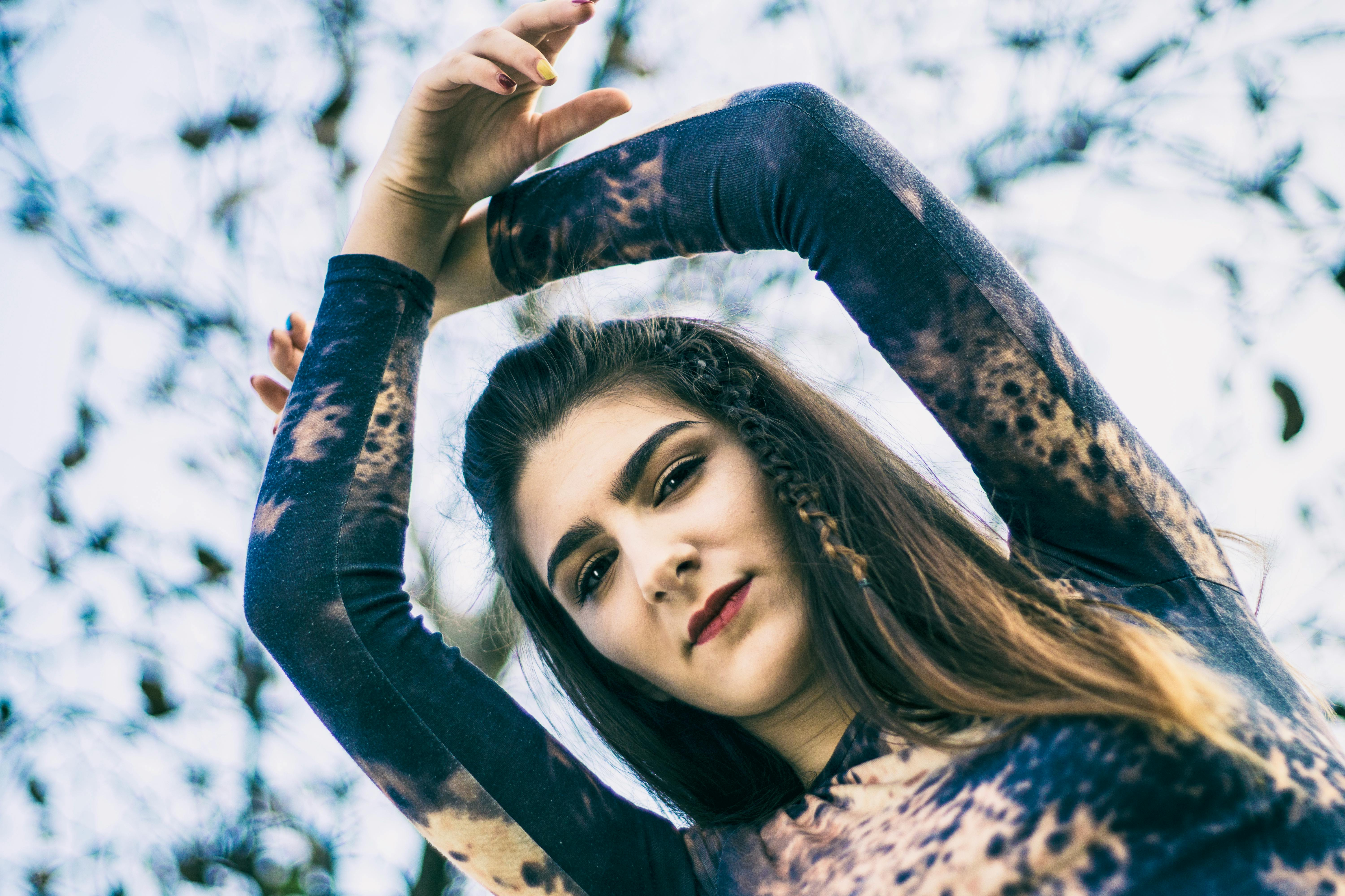 一位穿着充满活力服装的女性在户外拍摄的艺术肖像，她举起了双臂