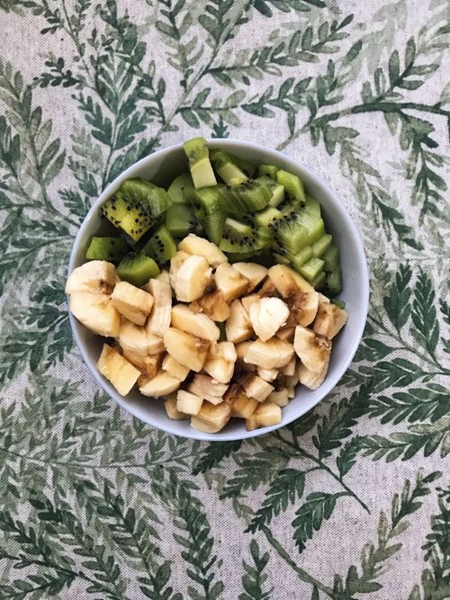 Free Freshly sliced kiwi and banana cubes in a bowl on a leafy patterned tablecloth. Stock Photo