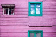 这栋木屋外观丰富多彩，粉色的墙壁与鲜亮的绿色窗户形成了大胆的对比