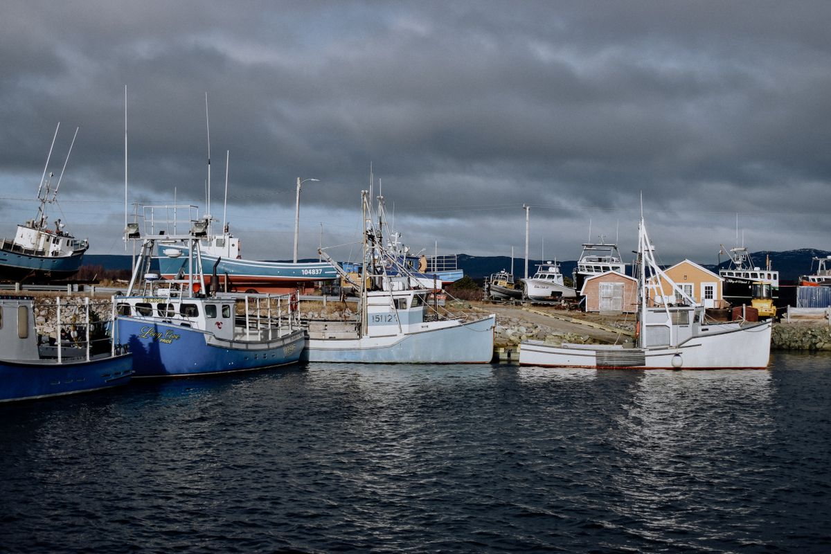 Fishing trawlers moored in a harbour under dark clouds