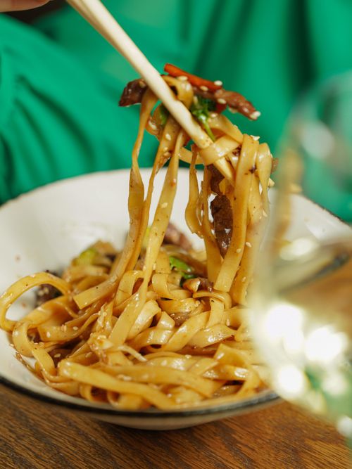 Free Delicious Asian noodles served in a bowl, lifted by chopsticks. Perfect for food blogs. Stock Photo