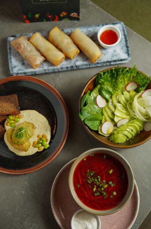 Free A vibrant spread of vegan dishes including spring rolls, soup, salad, and appetizers on a stone table. Stock Photo