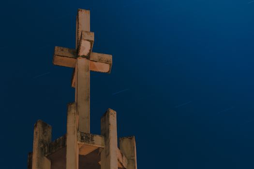A church tower with a cross silhouetted against a blue twilight sky in Geleen, Nederland.