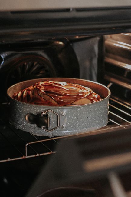 Close-up of a cake baking in a grey pan inside an oven, showcasing the process of baking.