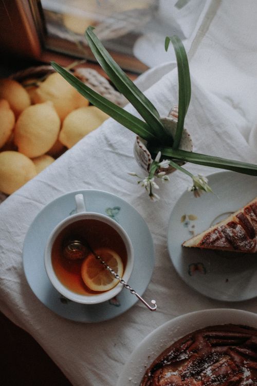 Free A warm cup of tea with lemon next to a cake slice, evoking a cozy afternoon ambiance. Stock Photo