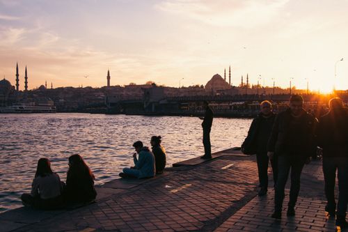 Free People enjoying the Istanbul waterfront at sunset with cityscape views of mosques and skyline. Stock Photo