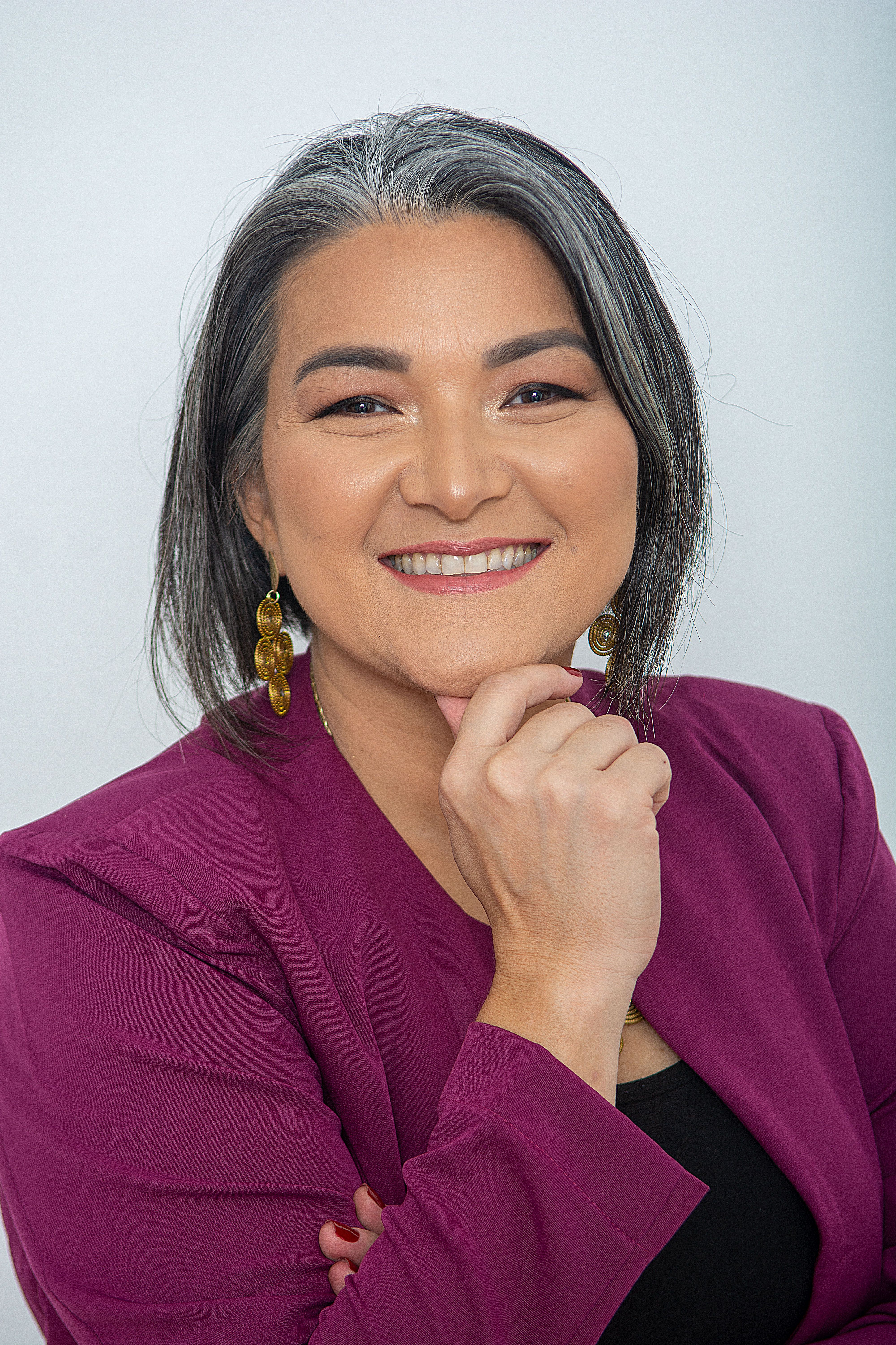 Smiling woman in business attire posing confidently against a white background.