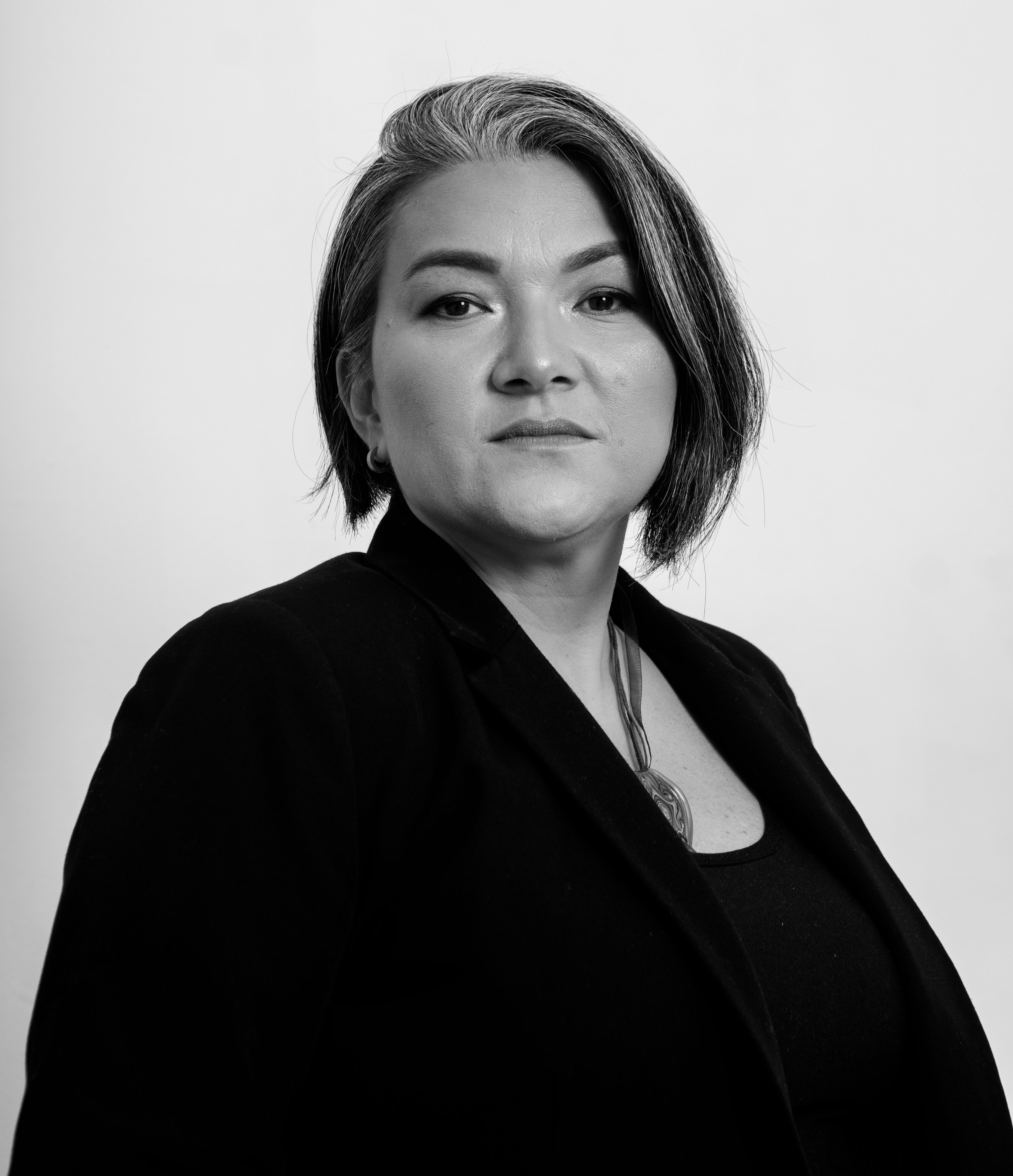 Black and white portrait of a confident woman posing with a neutral expression.