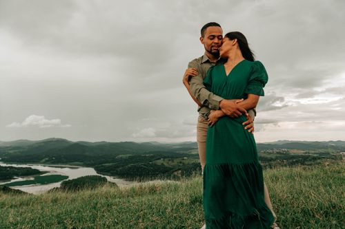 Free A couple embraces on a hilltop with a scenic landscape backdrop, capturing love and serenity. Stock Photo