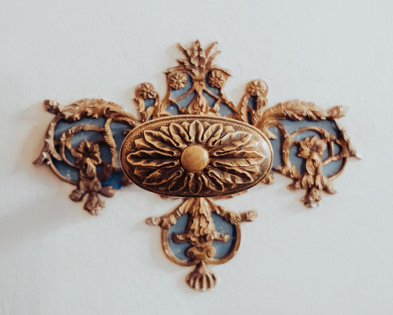 a close up of an intricately designed brass ornament on a white wall s