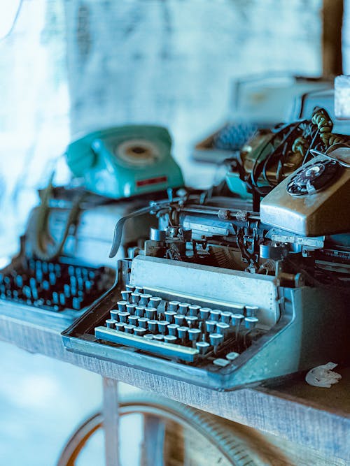 A Pile of Antique Typewriters and Telephones 