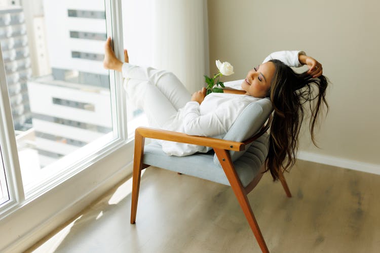 Brunette Relaxing With Rose On Chair