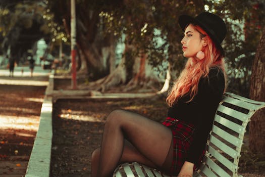 一位年轻女子，头发鲜艳，优雅地坐在公园长凳上，融入城市环境