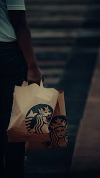 A person carries branded coffee shop bags on an outdoor street in Dubai, UAE.