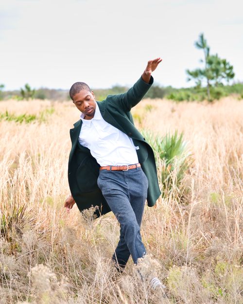 Free Fashionable man posing in an open field, showcasing modern menswear style. Stock Photo