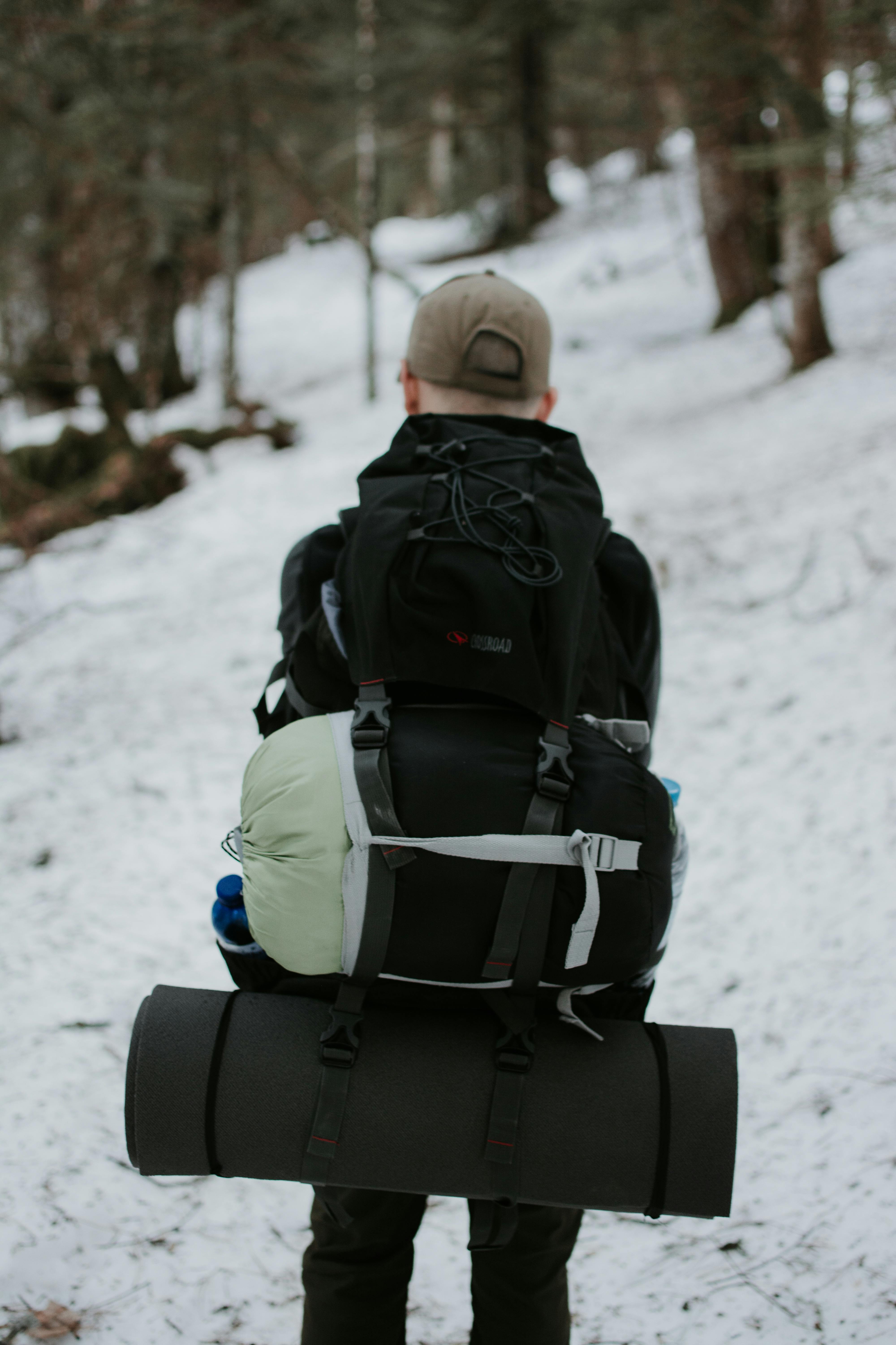 Randonneur avec grand sac à dos et équipement de camping dans une forêt enneigée