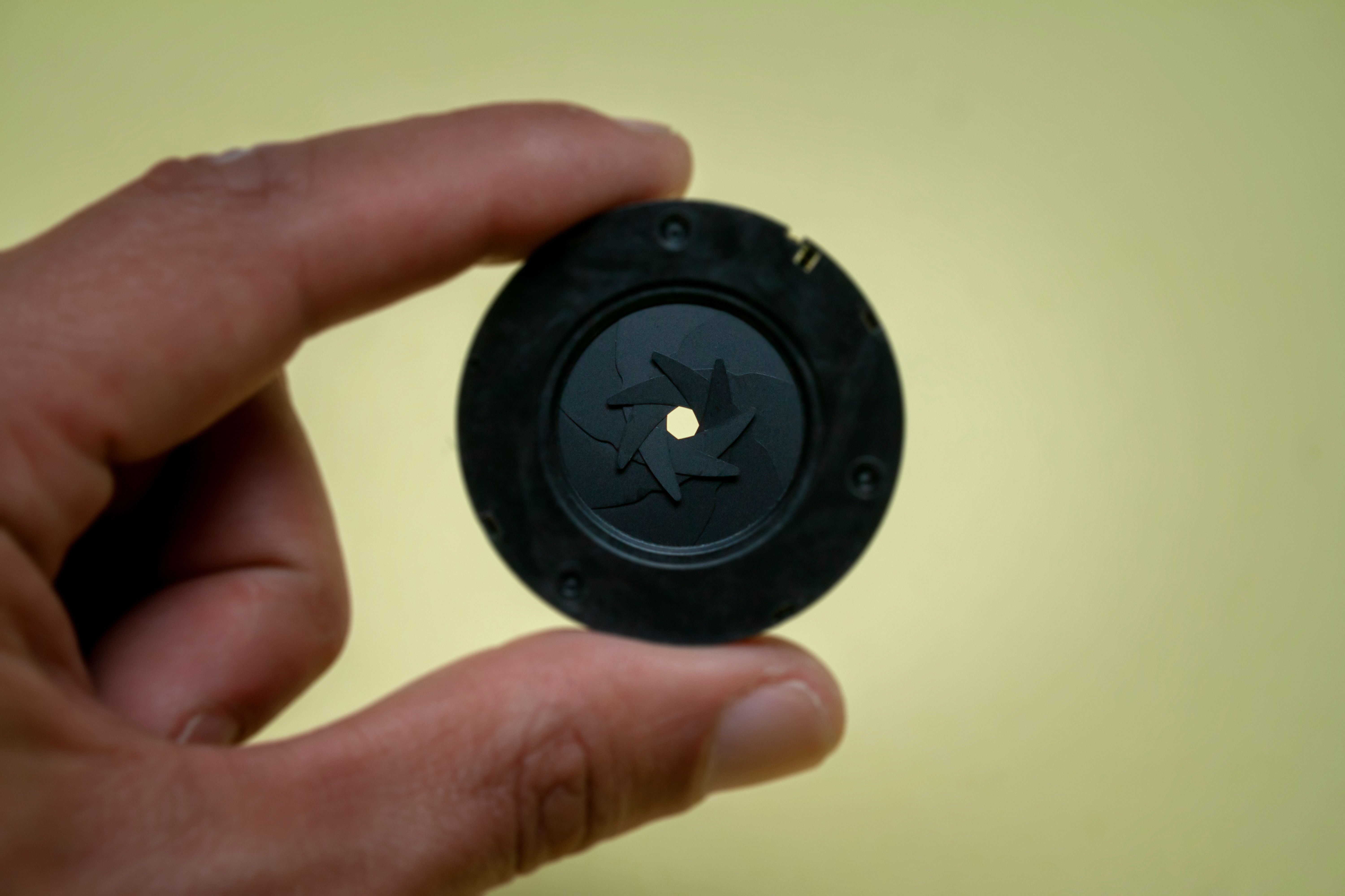 Detailed view of a hand holding a camera aperture demonstrating precision technology.