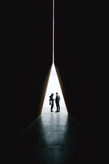 Silhouette of two people standing in a dramatic tunnel with light at the end in London.