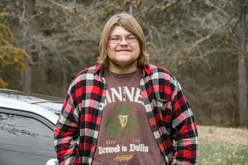 Young Man with Long Hair in Casual Clothes Standing Outdoors 