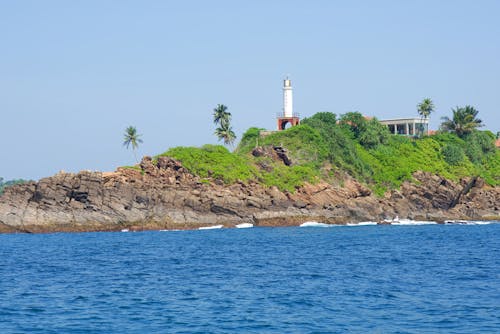 Sea Shore with Rocks on Coast and Lighthouse behind