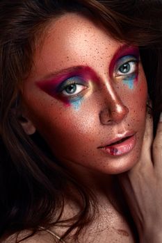 Close-up portrait of a woman with bold and vibrant artistic makeup, showcasing intense colors and creativity.