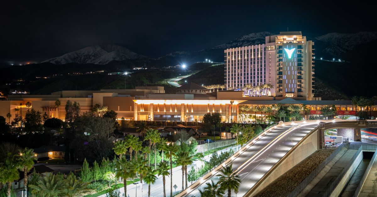 Stunning night view of Yaamava Resort & Casino in Highland, CA, illuminated against snowy mountains.