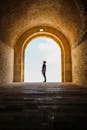 男子在古老的石砌拱门中探索历史建筑的剪影