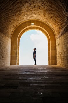 男子在古老的石砌拱门中探索历史建筑的剪影