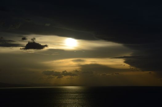 Moody seascape with dark clouds and sunset reflecting on ocean waves.