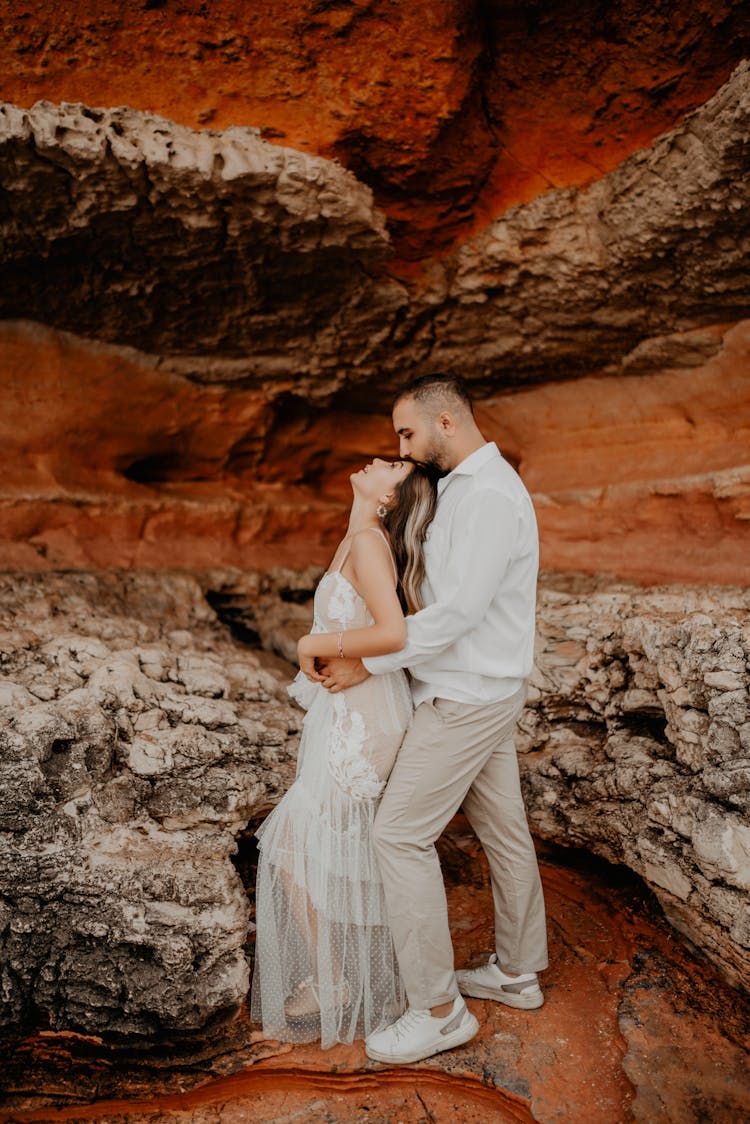 Man And Woman Hugging On The Background Of A Rocky Wall 