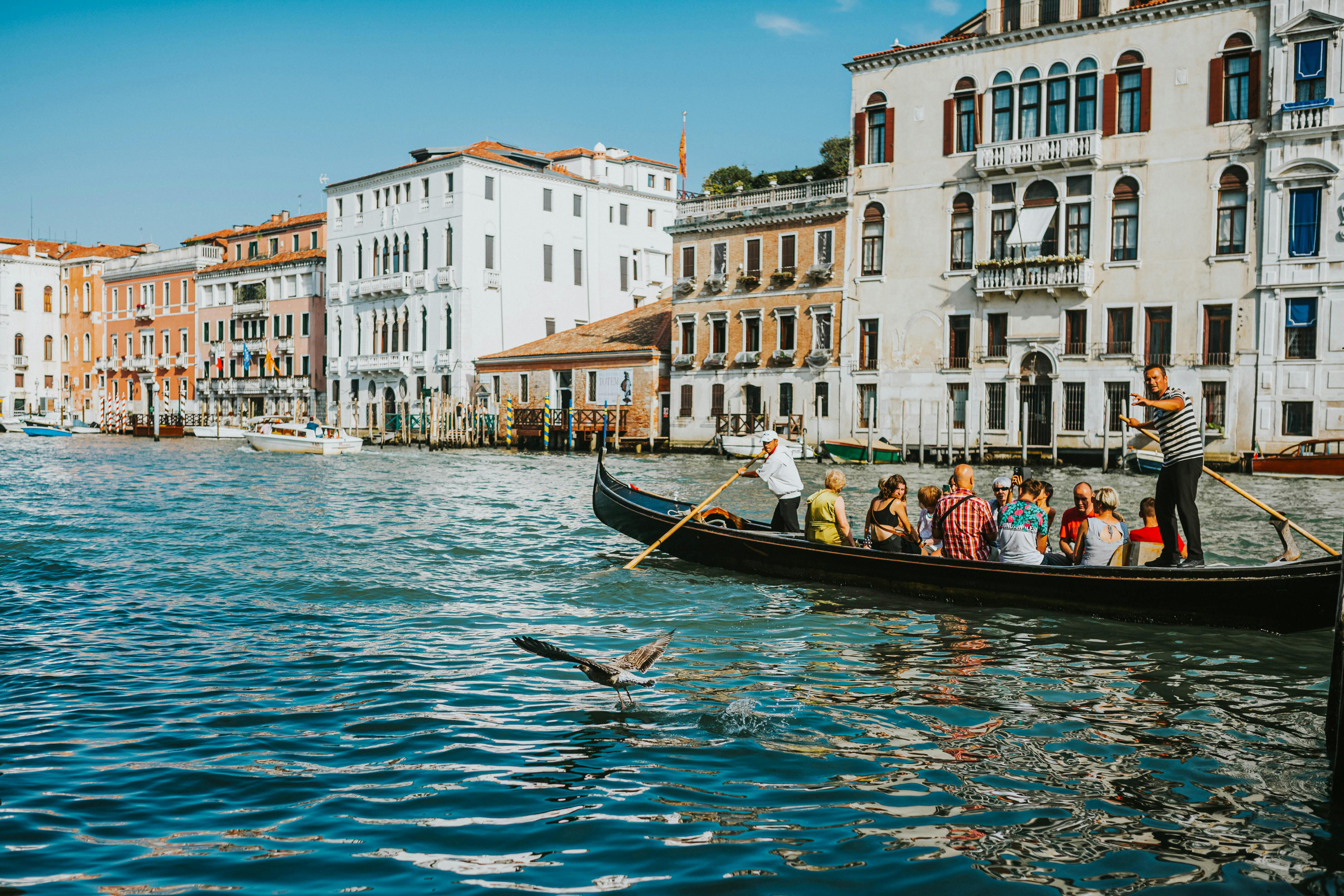 Scenic view of tourists enjoying a gondola ride on Venetian canals in Italy with historic buildings.