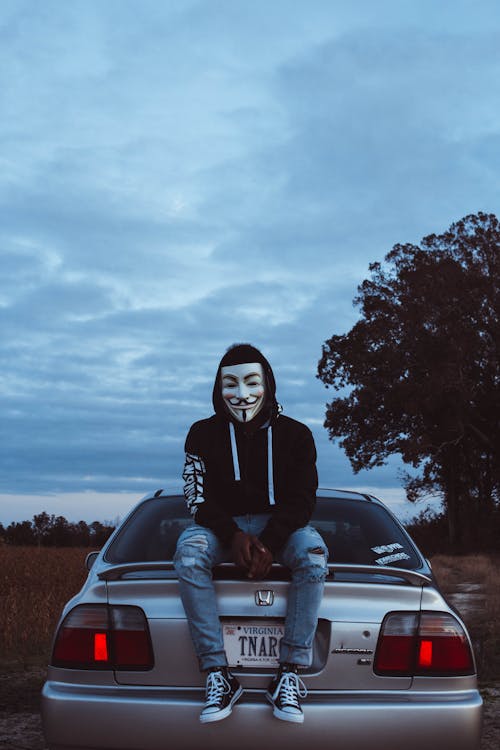 Free Man Wearing Guy Fawkes Mask While Sitting on Silver Honda Civic Stock Photo
