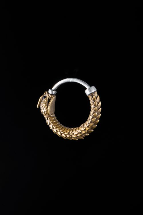 Free Luxurious golden ouroboros hoop earring against a black background, symbolizing eternity. Stock Photo