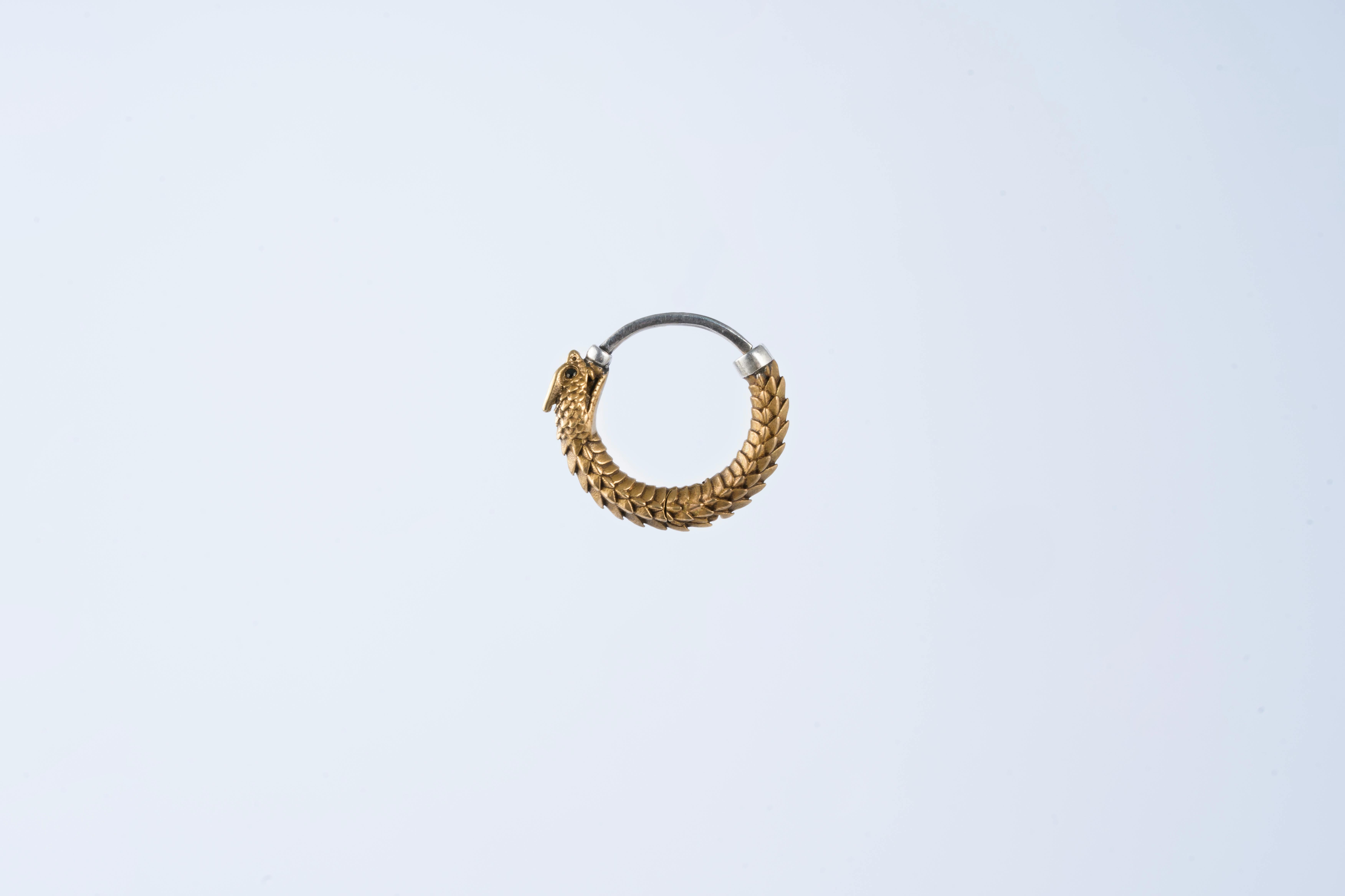 Free Detailed gold earring in circular design on a plain white background. Stock Photo