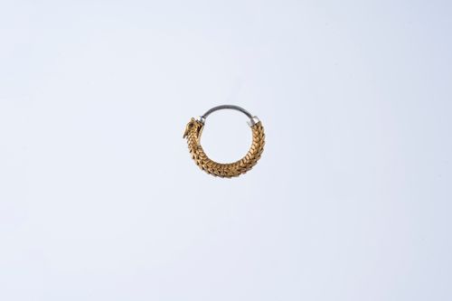 Free Detailed gold earring in circular design on a plain white background. Stock Photo