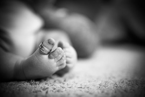 Black and White Photo of a Newborns Foot with a Ring