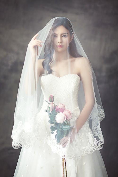 무료 흰색 베일에 덮여 장미 꽃다발과 흰색 끈이없는 연인 웨딩 드레스에 여자 스톡 사진