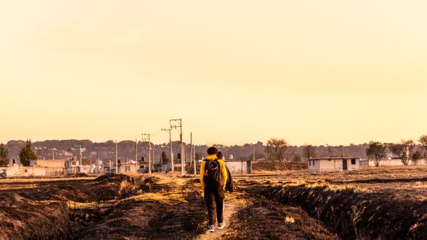 A person with a backpack walking along a rural path in Santa María Atarasquillo, Mexico, at sunset.