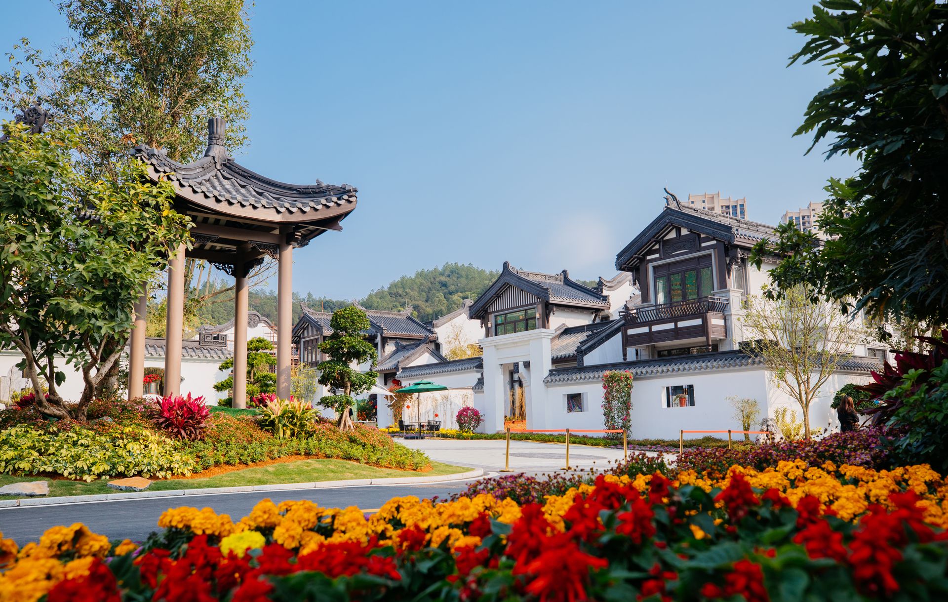 Scenic view of a traditional Japanese garden with vibrant flowerbeds and a charming gazebo in the backdrop.